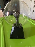 Front view of the plasma ball showing the glass globe, central electrode, and black base with power switch.