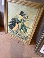Framed bullfighter scene painting leaning against a wall on a concrete floor, showing full artwork and frame.
