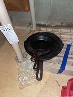 Top down view of three cast iron fry pans stacked, showing the varying sizes and handles.