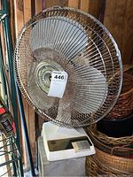 Front view of the Woolworth electric table top fan showing the protective wire cage, metal blades, and base with control panel.