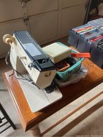 Photo of Singer Touchtronic 2000 sewing machine and a bin with sewing notions on a wooden table.