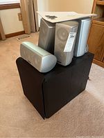Speakers arranged on and around the subwoofer with instruction manual on top, showing overall lot contents.