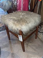 Front angle view of one wood framed stool with shag material top showing condition and materials