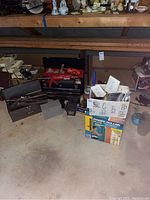 Wide shot of metal toolbox with hand tools, smaller toolboxes and box of Wagner Power Roller Plus and paint supplies in a garage setting.