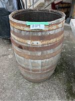Front view of a wooden barrel missing top and bottom, showing metal bands rusty and wood weathered.