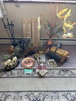 Overall shot of the lot showing copper vase, various animal sculptures including elephant and horses, fireplace tools, ceramic wall hangings, rug, and decorative items.