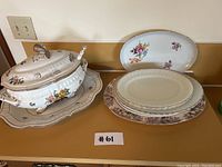 Full set of German made ceramics and china consisting of tureen, plates and serving platters on countertop.