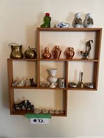 Full view of wooden shelf filled with various small figurines including metal, ceramic, and glass items.