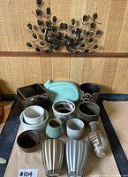 Photo showing assorted pottery including turquoise dish, black swirl pot, white bowls, various ceramic pots and vases.