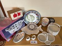 Group photo showing ceramic and glass serving plates, fish-shaped platter, condiment holders, small white ceramic woven baskets, and packaged items.