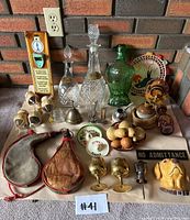 Photo showing entire lot of vintage bar accessories and decor on a table against a brick wall.