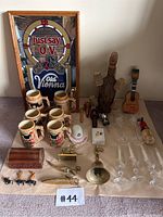 Overview of the lot showing beer steins, wooden guitar-shaped wine bottle holder, crystal champagne flutes, small decorative items, and Old Vienna beer clock sign.