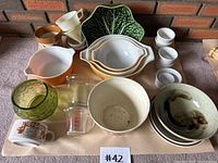 Overview photo of all items in the lot including Pyrex mixing bowls, ramekins, measuring cup, and assorted bowls and cups