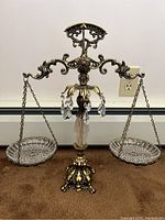 Front view of vintage decorative balance scale with glass pans and hanging crystals.