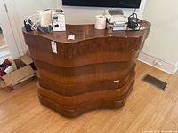 Front and right side view of the wavy wooden bar showing the layered horizontal design and veneer wear.