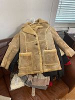 Tan shearling-style coat with patch pockets, button front, showing wear and stain marks
