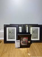 Four black IKEA 5x7 picture frames and one Things Remembered photo album with star decoration shown on a table against a wall.