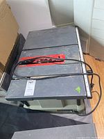 Top view of blue/grey table saw with red saw blade protector, power cord on top, and measuring scale along the edge.
