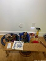 Shelf with various items including plaster fruit in blue bowl, wood candle holder, wooden cigar box, butterfly wall hook, and serving bowls.