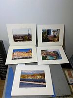 Set of five matted photos displayed on a surface, showing different city and coastal scenes approximately 10x8 in size.