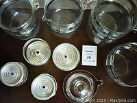 Top view of multiple clear glass Pyrex pots, percolator filter inserts with ridged metal bases, and round lids.
