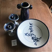 Four-piece Canadian studio pottery set with large round plate, tall vase with handles, and two candle holders on wooden table.