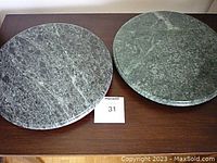 Top view showing two round marble lazy susans with natural veining, placed on a wooden surface.