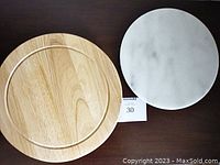 Overhead photo showing the round wooden cheese board and round marble lazy Susan side by side on a dark surface.