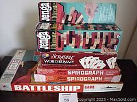 Lot of vintage board and drawing games stacked: Jenga Ultimate, Scrabble Word Rummy, two Kenner Spirograph sets, and Battleship board game.
