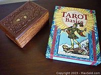 Wooden box with detailed carvings on the lid and Tarot Basics book beside it