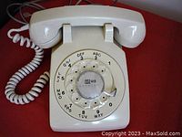 Front view of beige rotary dial telephone showing dial with area code and handset rested on base