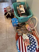 Photo shows basket with fabric items, shoes, winter boots, round placemats, extension cord, and florist arrangement.