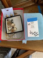 Open red box and blue box showing black felt insert containing loose gold-tone jewelry pieces