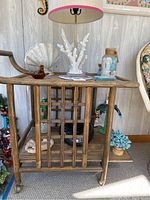 Front and side view of the bamboo bar cart with beach-themed decor on top and the coral lamp.
