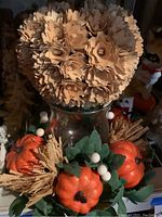 Artificial pumpkin centerpiece with flowers on glass container