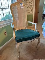 Armchair showing carved wooden frame, cane back, and green upholstered seat cushion.