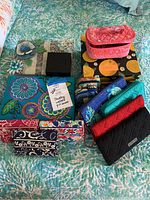 Photo showing assorted wallets, jewelry boxes, pill box wallets and jewelry arranged on a bedspread
