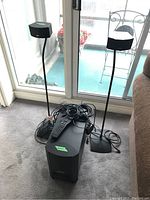 Front view of the subwoofer, two standing speakers, remote control and cables