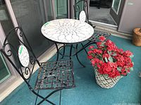 Full view of metal cafe set with mosaic tile designs and potted faux flowers.