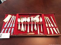 Full view of the open wood canteen showing the 8-piece stainless steel flatware set with additional serving pieces arranged in red felt lining.