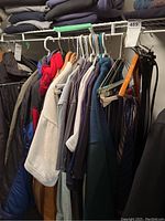 View of assorted men's coats, golf shirts, ties, and belts on rack