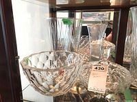 Front angle photo showing the Orrefors signed cut crystal bowl with diamond pattern, and behind it, cross & olive style bowl and multiple clear glass vases.