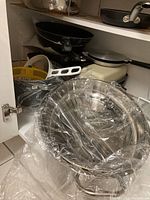 Assorted pots and pans stacked inside a cabinet including frying pans, saucepans and others.