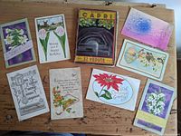 Top view of 8 colorful vintage and antique postcards spread out on wooden surface along with small travel booklet titled Capri showing colorful cover with cave image.