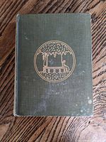 Front cover of green hardcover book showing gold embossed illustration and some wear spots.