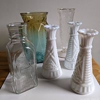 Overview of five glass items: honey jar, blue/gold vase, clear textured vase, and three white milk glass vases.