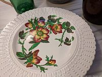 Close-up of decorative floral plate with white raised dotted border.