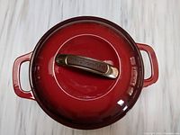 Top view of the red enameled cast iron Dutch oven lid with brass-toned Kitchen Aid handle.