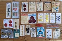 Full view of multiple assorted vintage button cards and sewing notions laid flat on wooden surface.