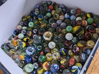 Close-up of various colorful glass marbles in a box showing different sizes and patterns